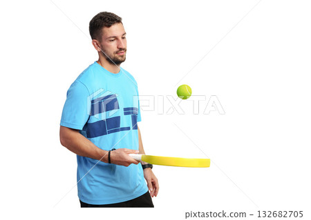 Young man playing with a yellow paddle and tennis ball indoors Young man playing with a yellow paddle and tennis ball indoors 132682705