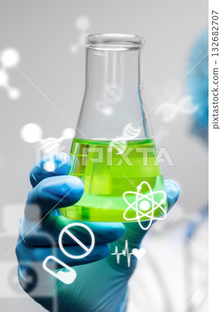 Scientist holds green liquid in laboratory flask during chemical experiment Scientist holds green liquid in laboratory flask during chemical experiment 132682707