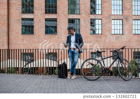 City commuter riding bike from work, reading text message on phone. City commuter riding bike from work, reading text message on phone. 132682721