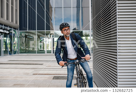 Man riding bike to work in city with helmet and backpack Man riding bike to work in city with helmet and backpack 132682725