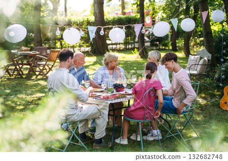 Family sharing food during garden grill party. Family sharing food during garden grill party. 132682748