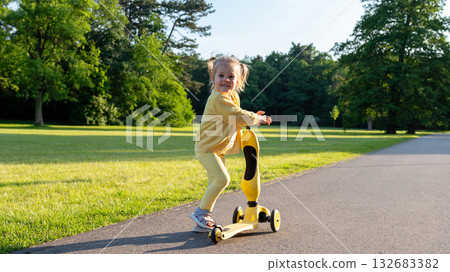 Child scooter riding. Girl yellow scooter park. Motion day lifestyle travel. 132683382
