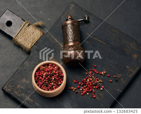 Antique copper pepper shaker and red dried peppercorns on a dark wooden board Antique copper pepper shaker and red dried peppercorns on a dark wooden board 132683425