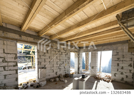 House room interior under construction and renovation. Energy saving walls of hollow foam insulation blocks, wooden ceiling beams and roof frame. 132683486