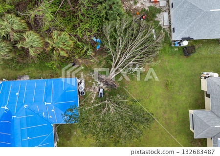 Home rooftop wrapped in plastic tarp following hurricane damage, protecting structure from water penetration until permanent roofing materials are restored 132683487