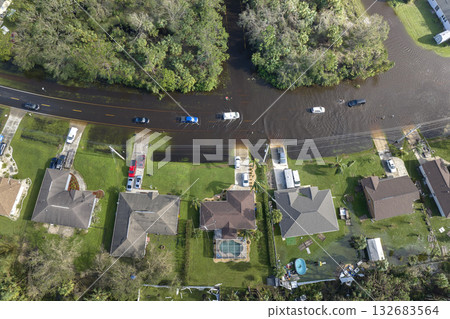 Flooded Florida road with evacuating cars and surrounded with water houses in suburban residential area. Consequences of hurricane natural disaster Flooded Florida road with evacuating cars and surrounded with water houses in suburban residential area. Consequences of hurricane natural disaster 132683564