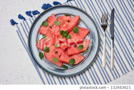 Bright, juicy watermelon slices with mint leaves served on a plate. Top view. 132683621