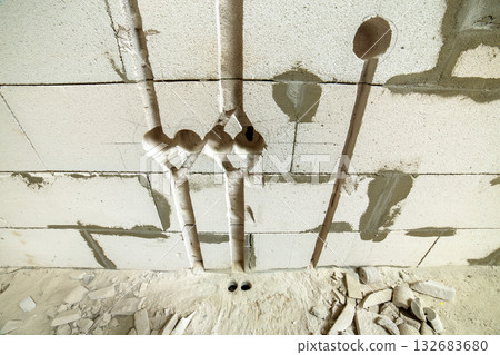 Deep grooves and holes in white brick wall made for installation of electrical cables. 132683680