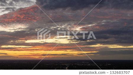 Colorful sunset sky over rural area. Setting sun behind vivid orange and yellow clouds Colorful sunset sky over rural area. Setting sun behind vivid orange and yellow clouds 132683707