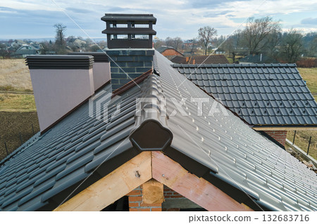 Closeup of house roof top covered with ceramic shingles. Tiled covering of building under construction Closeup of house roof top covered with ceramic shingles. Tiled covering of building under construction 132683716