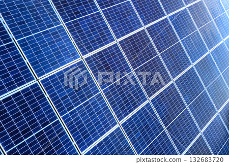 Close-up surface of lit by sun blue shiny solar photo voltaic panels. System producing renewable clean energy. Renewable ecological green energy production concept. Close-up surface of lit by sun blue shiny solar photo voltaic panels. System producing renewable clean energy. Renewable ecological green energy production concept. 132683720