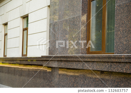 Close up view of part of a building facade with the surface of granite wall. Natural stone materials. Close up view of part of a building facade with the surface of granite wall. Natural stone materials. 132683757