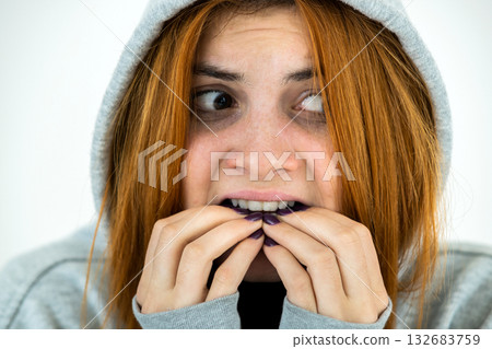 Close up portrait of scared young redhead woman wearing warm hoodie pullover. Close up portrait of scared young redhead woman wearing warm hoodie pullover. 132683759