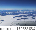 Aerial View Over Snowy Mountain Range With Clouds From An Airplane Window 132683838