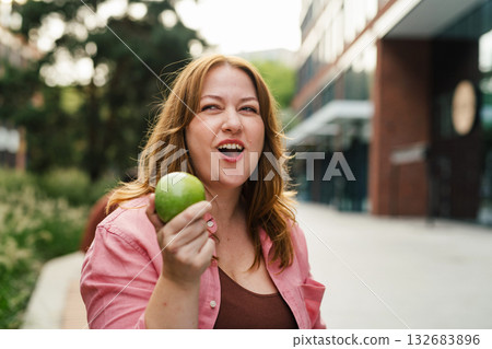 Plus size woman holding green apple. Plus size woman holding green apple. 132683896