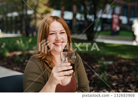 Plus size woman drinking soft soda drink with her lunch. 132683908