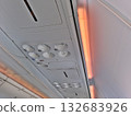 Interior of Airplane Cabin Overhead Panel and Warm Reading Light on Modern Jet 132683926