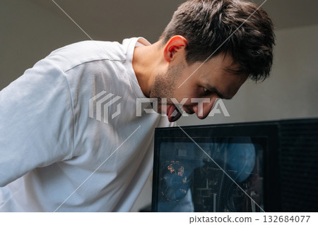 Cheerful computer technician male licking a dusty computer case with funny and frustrated expression, highlighting challenges of computer maintenance and repair. Concept of desktop PC service. Cheerful computer technician male licking a dusty computer case with funny and frustrated expression, highlighting challenges of computer maintenance and repair. Concept of desktop PC service. 132684077