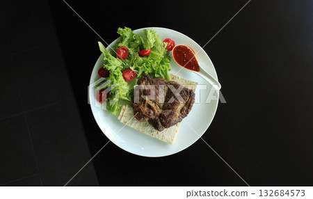 Fried meat steak with greens on wooden table isolated Fried meat steak with greens on wooden table isolated 132684573