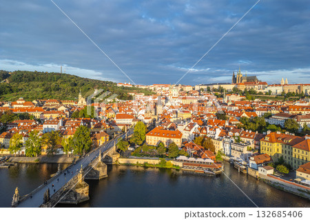 Early morning light casts a warm glow over the historic skyline of Prague. The vibrant rooftops and serene Vltava River create a picturesque scene with the iconic Charles Bridge in view. Early morning light casts a warm glow over the historic skyline of Prague. The vibrant rooftops and serene Vltava River create a picturesque scene with the iconic Charles Bridge in view. 132685406