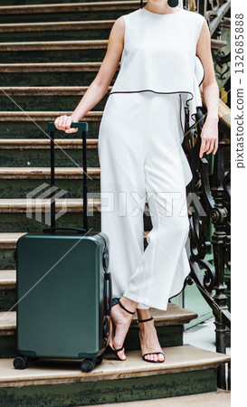 An elegant woman with luggage on stairs. An elegant woman with luggage on stairs. 132685888