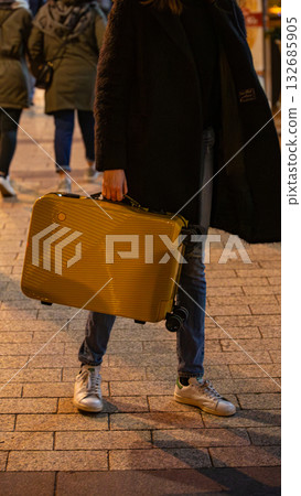 A traveler carries a bright suitcase on a city street. A traveler carries a bright suitcase on a city street. 132685905
