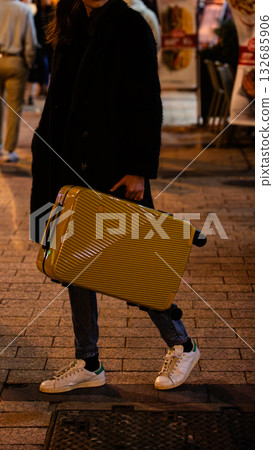 A traveler carries a bright suitcase on a city street. A traveler carries a bright suitcase on a city street. 132685906