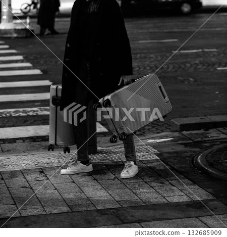 A chic traveler waits with two suitcases. A black and white concept for urban journeys, life choices, and mysterious departures. 132685909