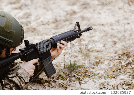 Soldier in tactical gear aims a rifle. 132685927