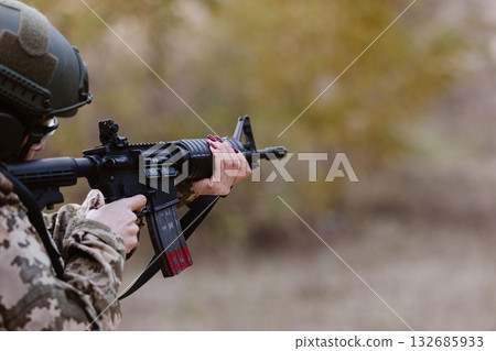 A woman in camouflage aims a rifle. A woman in camouflage aims a rifle. 132685933
