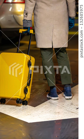 A traveler follows an arrow with a bright yellow suitcase. A traveler follows an arrow with a bright yellow suitcase. 132685975