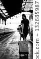 A woman with luggage on a train platform. 132685987
