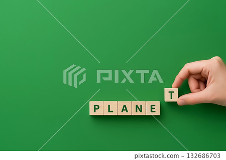 Wooden cubes spelling the word PLANET, a hand completes the word 132686703