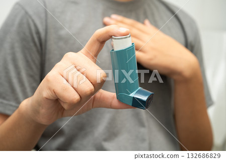 Asthma and chronic obstructive pulmonary disease COPD, Asian young man using metered dose inhaler MDI. 132686829