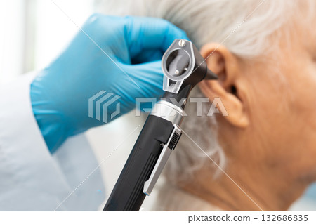 Audiologist or ENT doctor use otoscope checking ear of asian senior woman patient treating hearing loss problem. Audiologist or ENT doctor use otoscope checking ear of asian senior woman patient treating hearing loss problem. 132686835