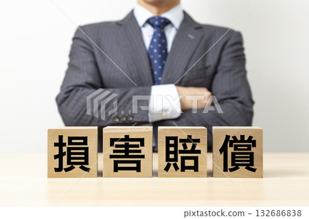 一位商人雙手交叉放在胸前，旁邊立著一塊寫著「損害賠償」的牌子。 132686838