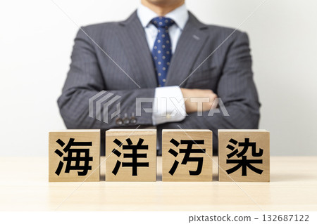 A businessman with his arms crossed and a block that reads "Marine Pollution" A businessman with his arms crossed and a block that reads "Marine Pollution" 132687122