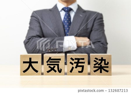 A businessman with his arms crossed and a block that reads "Air Pollution" A businessman with his arms crossed and a block that reads "Air Pollution" 132687213