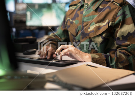 Air force combat control officer typing on keyboard, performing tactical level surveillance, close up. Military specialist using radar to search for potential assault zones, inputting coordinates 132687268