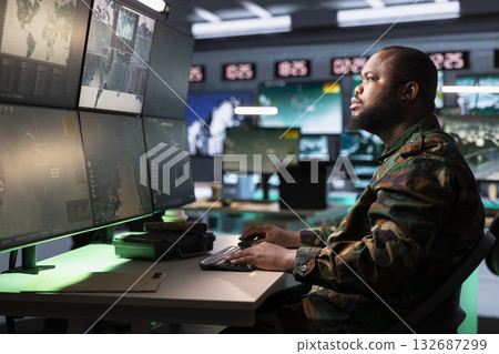 Army dispatcher working in command center housing operational missile defense system designed to intercept and destroy ballistic rockets. African american man tracking missiles using radar systems Army dispatcher working in command center housing operational missile defense system designed to intercept and destroy ballistic rockets. African american man tracking missiles using radar systems 132687299