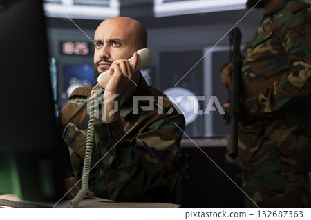Military expert in telephone call offering information to commanders fighting on front lines. Army professional providing intel for troops in base of operations using phone Military expert in telephone call offering information to commanders fighting on front lines. Army professional providing intel for troops in base of operations using phone 132687363