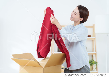 A woman putting clothes into a cardboard box A woman putting clothes into a cardboard box 132687834