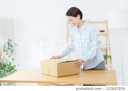 一名女子正在紙箱裡打包 一名女子正在紙箱裡打包 132687839