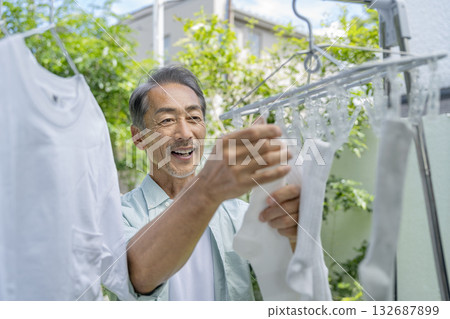 A man in his 60s hanging out laundry A man in his 60s hanging out laundry 132687899