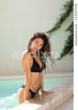 Confident woman in black bikini leaning on Confident woman in black bikini leaning on 132687946