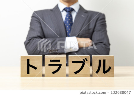 A businessman with his arms crossed and a block that reads "Trouble" 132688047