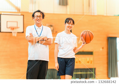 一名男老師和一名女學生在體育館拿著籃球 132688142