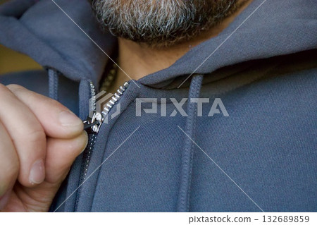 Bearded man zipping grey hoodie close up Bearded man zipping grey hoodie close up 132689859