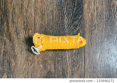 a skein of yellow nylon rope on a wooden brown background 132690272