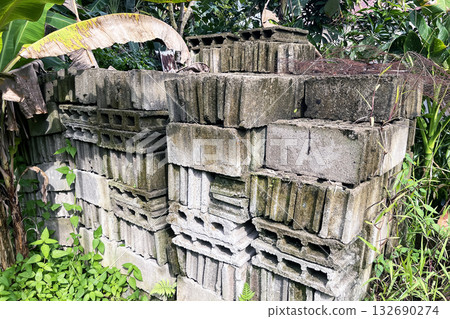 a stack of old hollow concrete blocks overgrown with grass 132690274